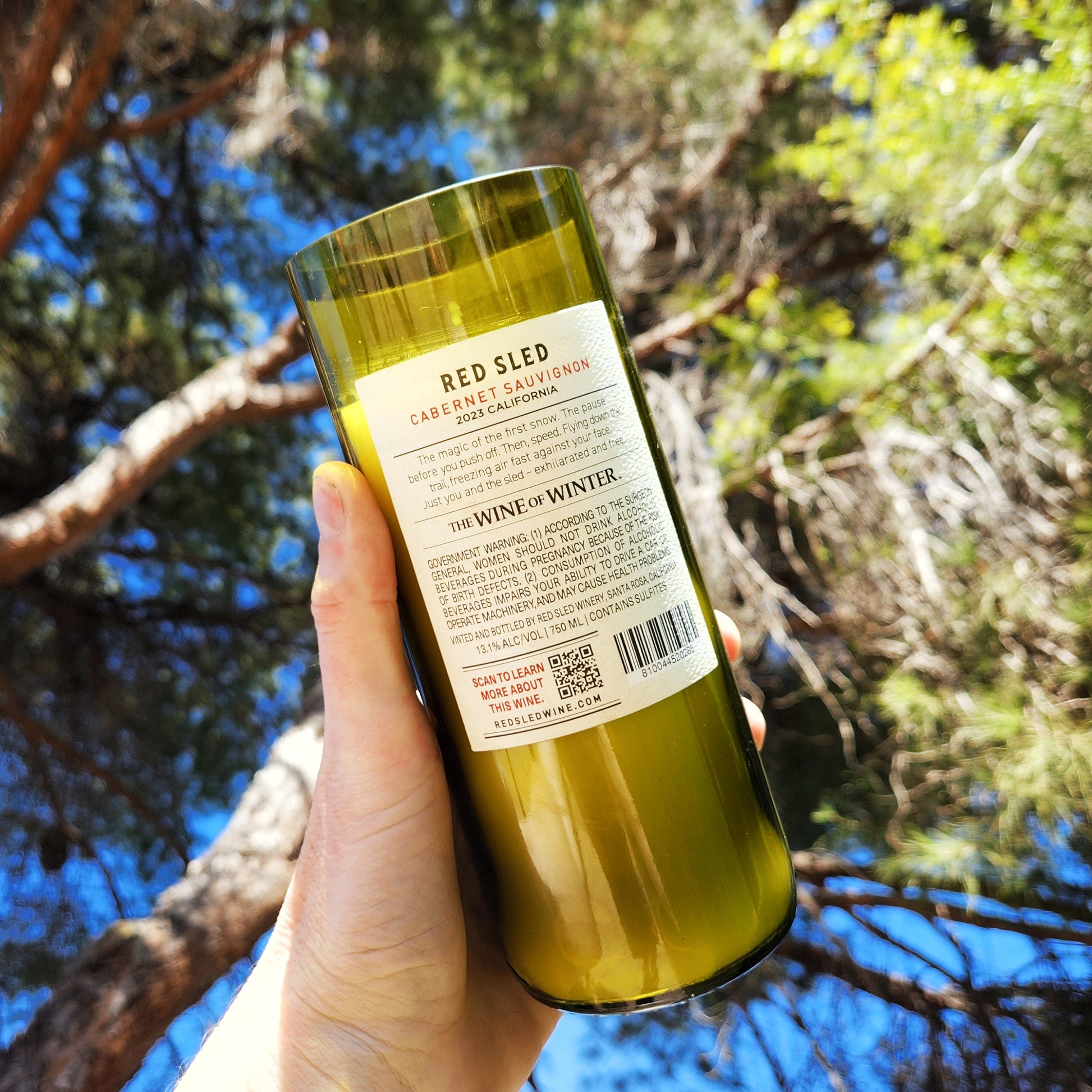 Back view of a Red Sled Cabernet Sauvignon wine bottle candle with original winery label intact, crafted into a sustainable candle using coconut soy wax and a wooden wick.
