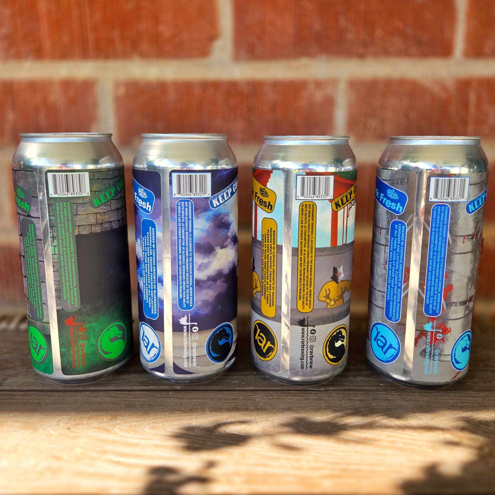 Rear view of four recycled beer cans turned into candles, showing the detailed back label artwork and brewing information. Each can retains its vibrant theme while housing a clean-burning coconut soy wax candle.