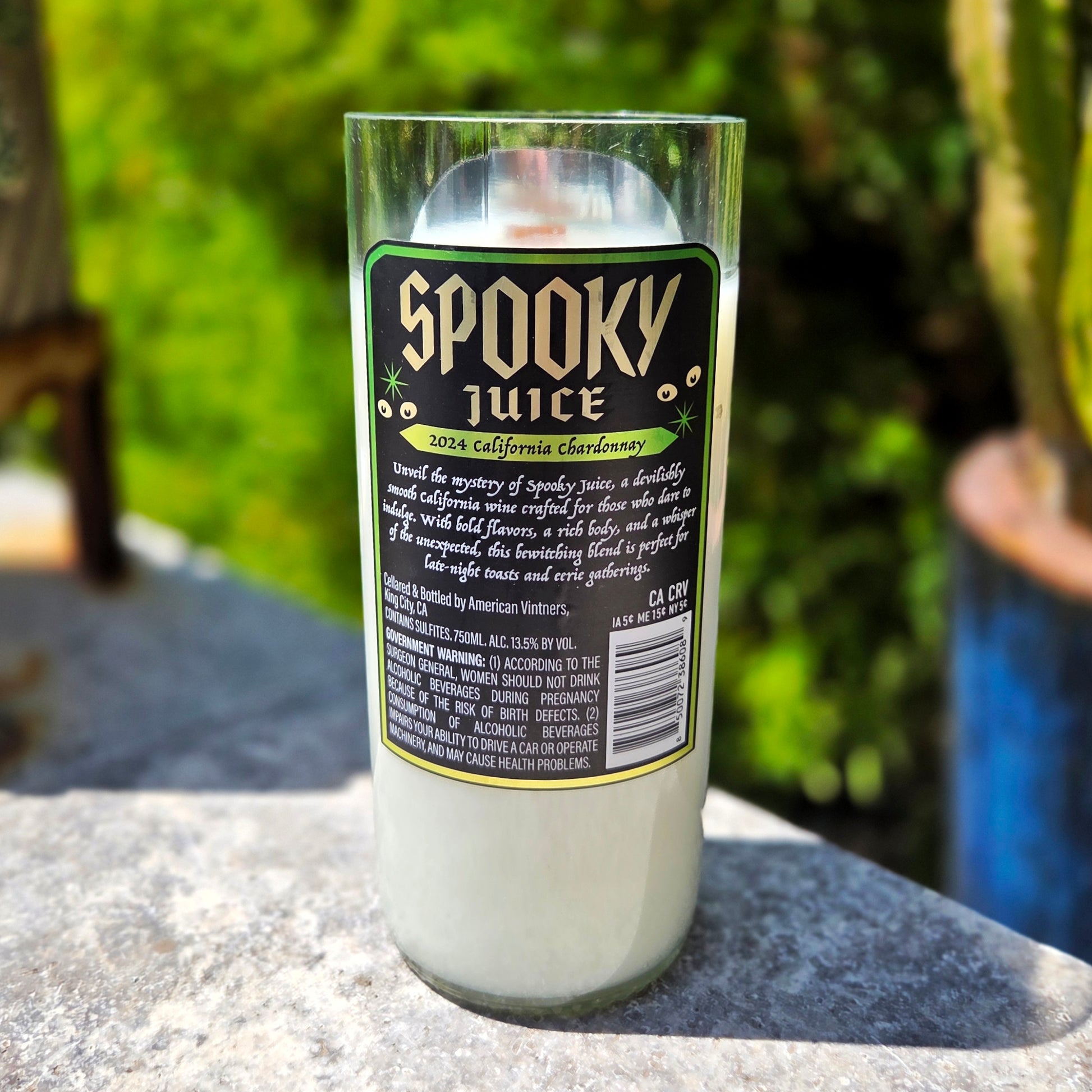 Recycled wine bottle candle featuring the “Spooky Juice” Chardonnay label with bold gothic lettering and detailed product story. Hand-poured with coconut soy wax and a wooden wick for a clean, eco-friendly burn.