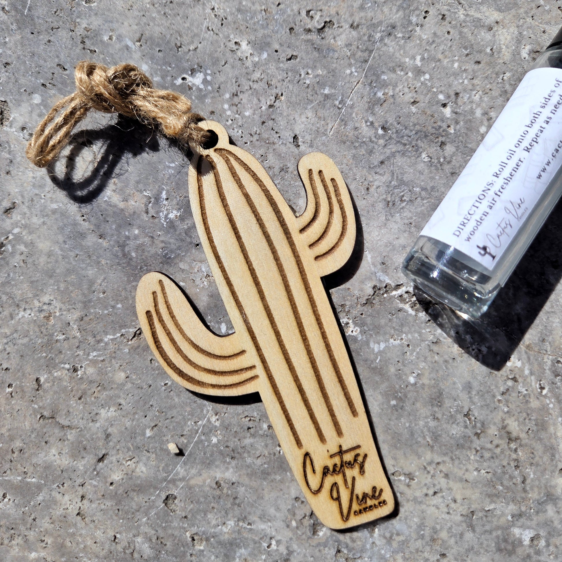 Wooden cactus air freshener with a rope and bottle on a concrete surface