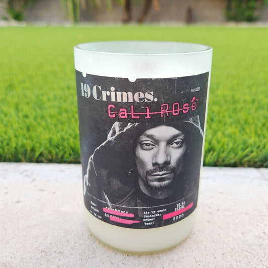 Front-facing image of a 19 Crimes Cali Rosé candle, featuring Snoop Dogg’s signature label on a frosted recycled bottle with hand-poured coconut soy wax and a wooden wick.

