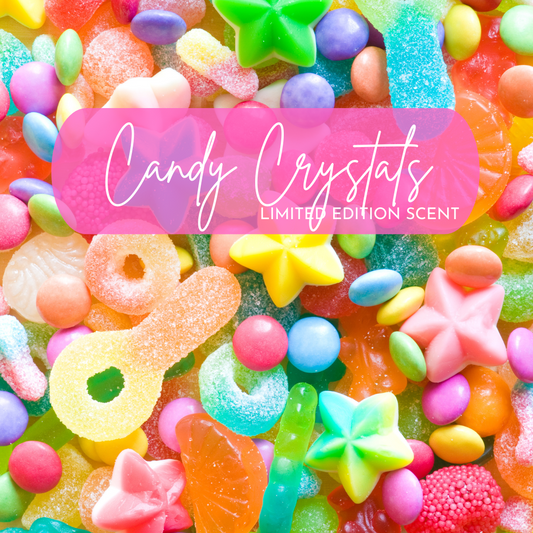 A vibrant, close-up image of assorted colorful candies including gummy keys, stars, worms, licorice, jelly rings, and chocolate buttons. A translucent pink overlay centered in the image reads "Candy Crystals – Limited Edition Scent" in whimsical white script. The bright mix of sweets visually evokes a sugary, playful scent inspiration.
