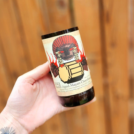 Full view of the 8-Bit Aleworks candle, showing the full pixel art Mayan warrior label and beer name “Barrel Aged Mayan Chocolossus.” The design combines whimsical gaming aesthetics with artisanal candle making.

