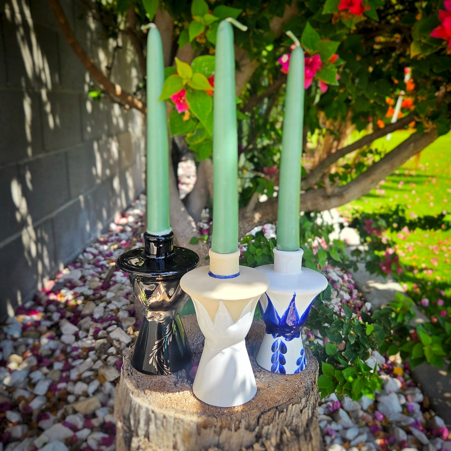 3 taper candlestick holders from ceramic hand painted bottle tops set outdoors.