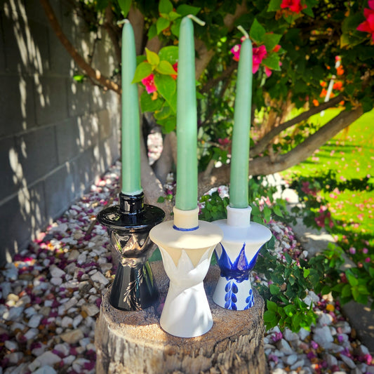 3 taper candlestick holders from ceramic hand painted bottle tops set outdoors.