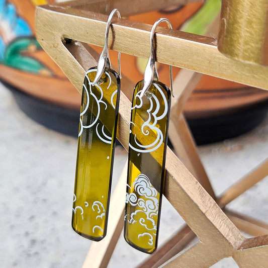 Pair of glass earrings with cloud design hanging on a wooden stand.