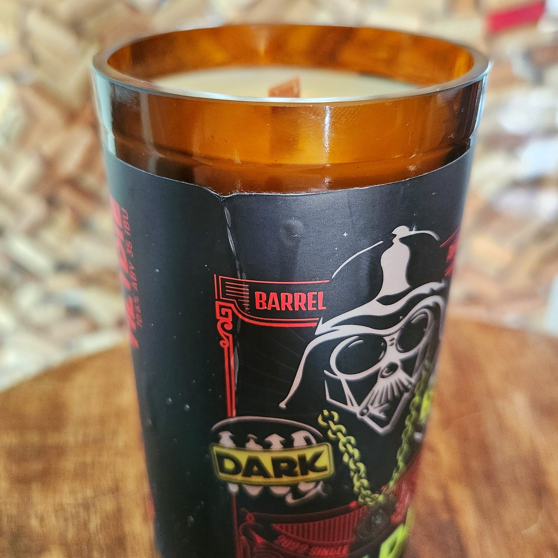 Detail view of the candle’s label showing a small ripple near the rim—one of the handmade quirks that adds to the charm of this upcycled beer bottle candle. The crackling wooden wick and non-toxic wax remain untouched.