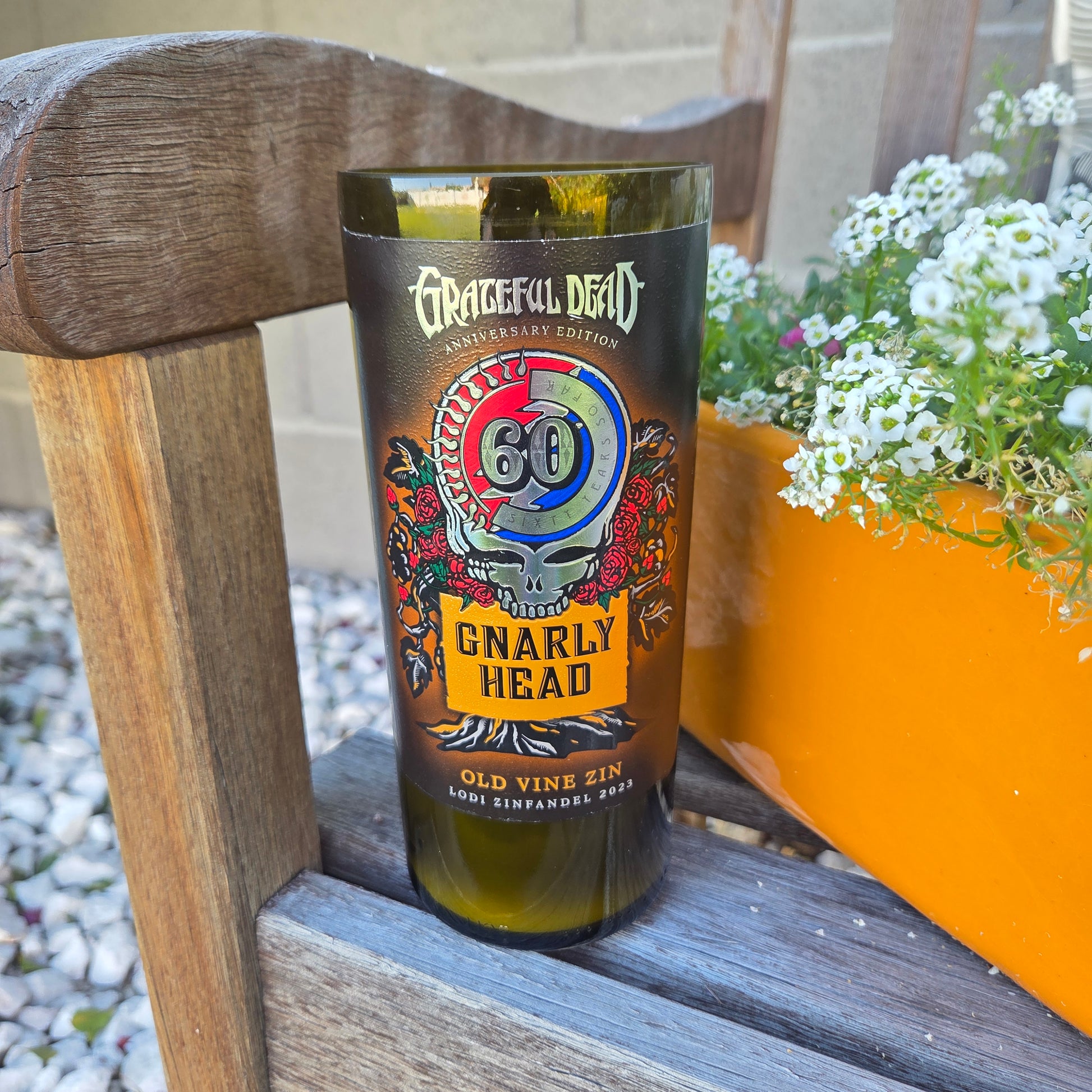 Gnarly Head wine bottle candle on a wooden chair with flowers in the background
