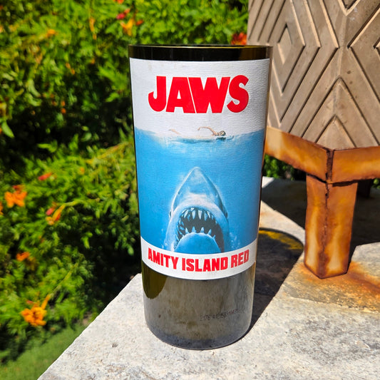 Front-facing Jaws inspired wine bottle candle with bold shark artwork and Amity Island Red label, hand-poured into a recycled bottle with coconut soy wax and wooden wick.