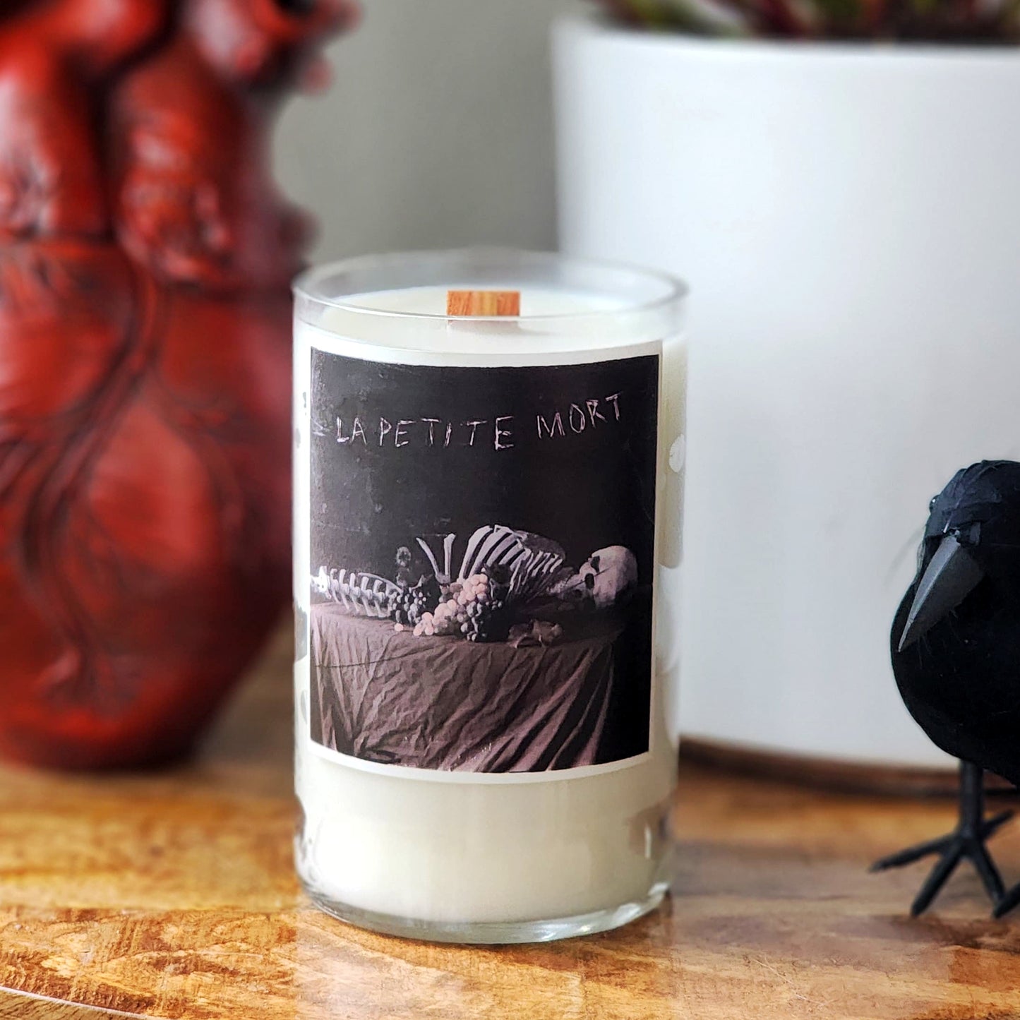 Candle with a skeleton design on the label, placed on a wooden surface.