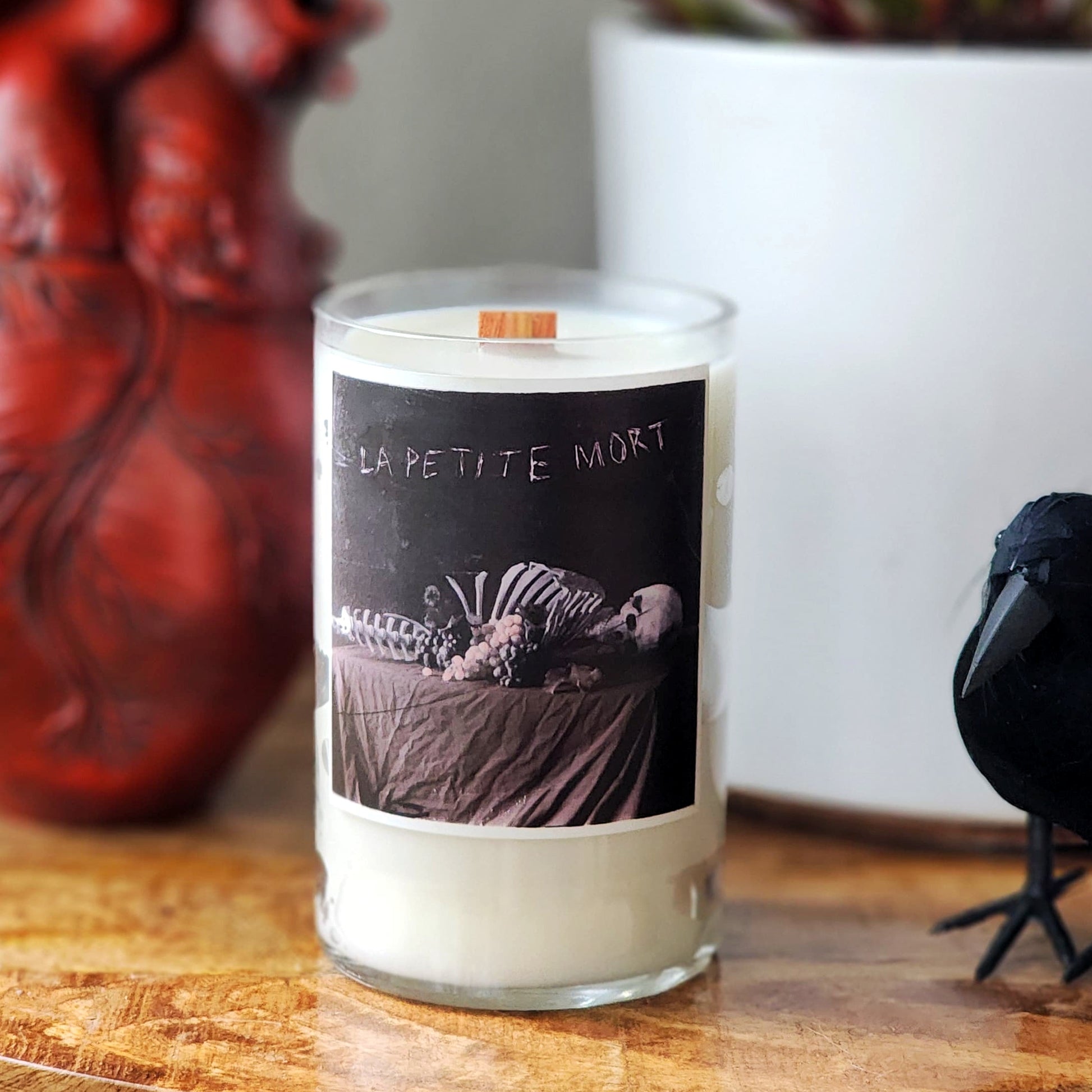 Candle with a skeleton design on the label, placed on a wooden surface.