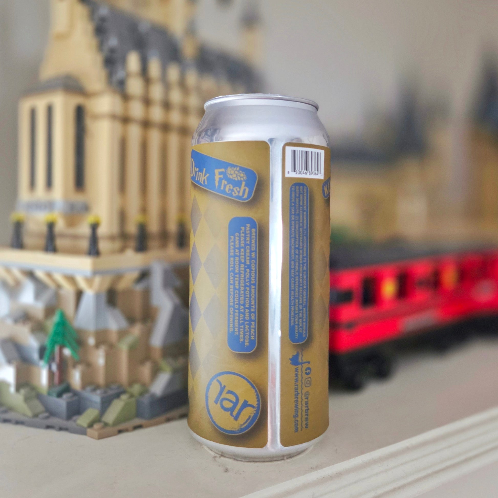 Back view of a beer can candle made from a “Drink Fresh” RAR Brewing can, repurposed into an upcycled candle. The gold and blue argyle label remains intact, showcasing the unique origin of this clean-burning recycled bottle candle.