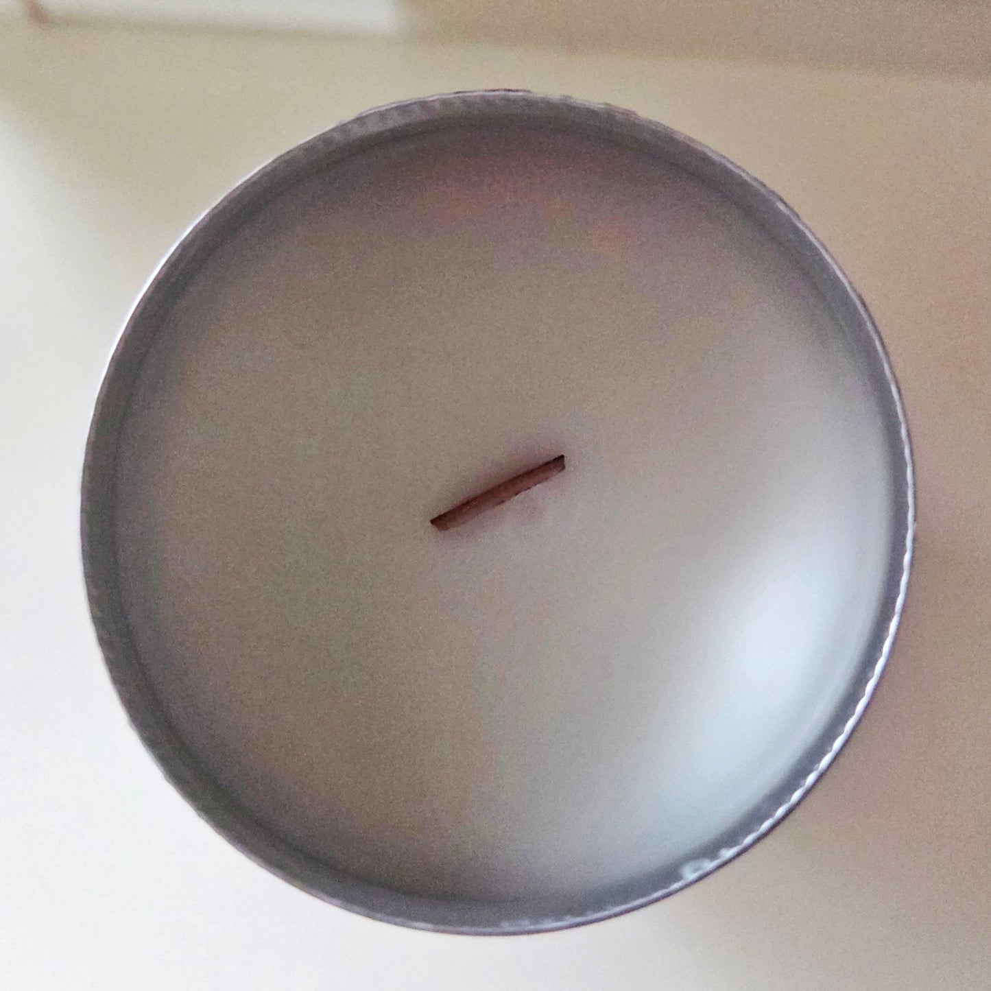 Top-down view of a repurposed beer can candle featuring clean, creamy coconut soy wax and a centered wooden wick. The smooth rim highlights the eco-friendly craftsmanship of this recycled vessel candle.