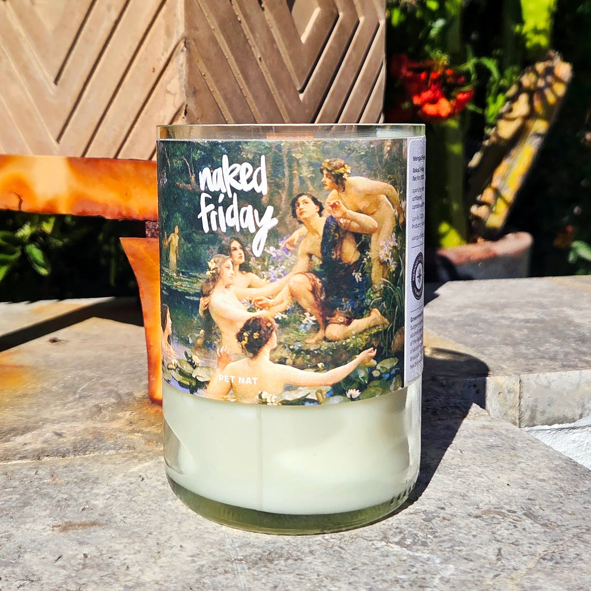 wine bottle Candle with 'naked Friday' label featuring classical painting design on a stone surface.