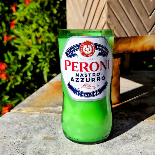A hand-poured eco-friendly beer bottle candle made from a recycled Peroni Nastro Azzurro bottle. The 7oz candle features smooth green glass with a crisp Italian label and is filled with coconut soy wax and a wooden wick. Perfect for sustainable décor lovers, this upcycled wine bottle candle showcases a clean, modern look with a sunny Orange Grove scent—orange blossom and sandalwood—for a fresh citrus glow.