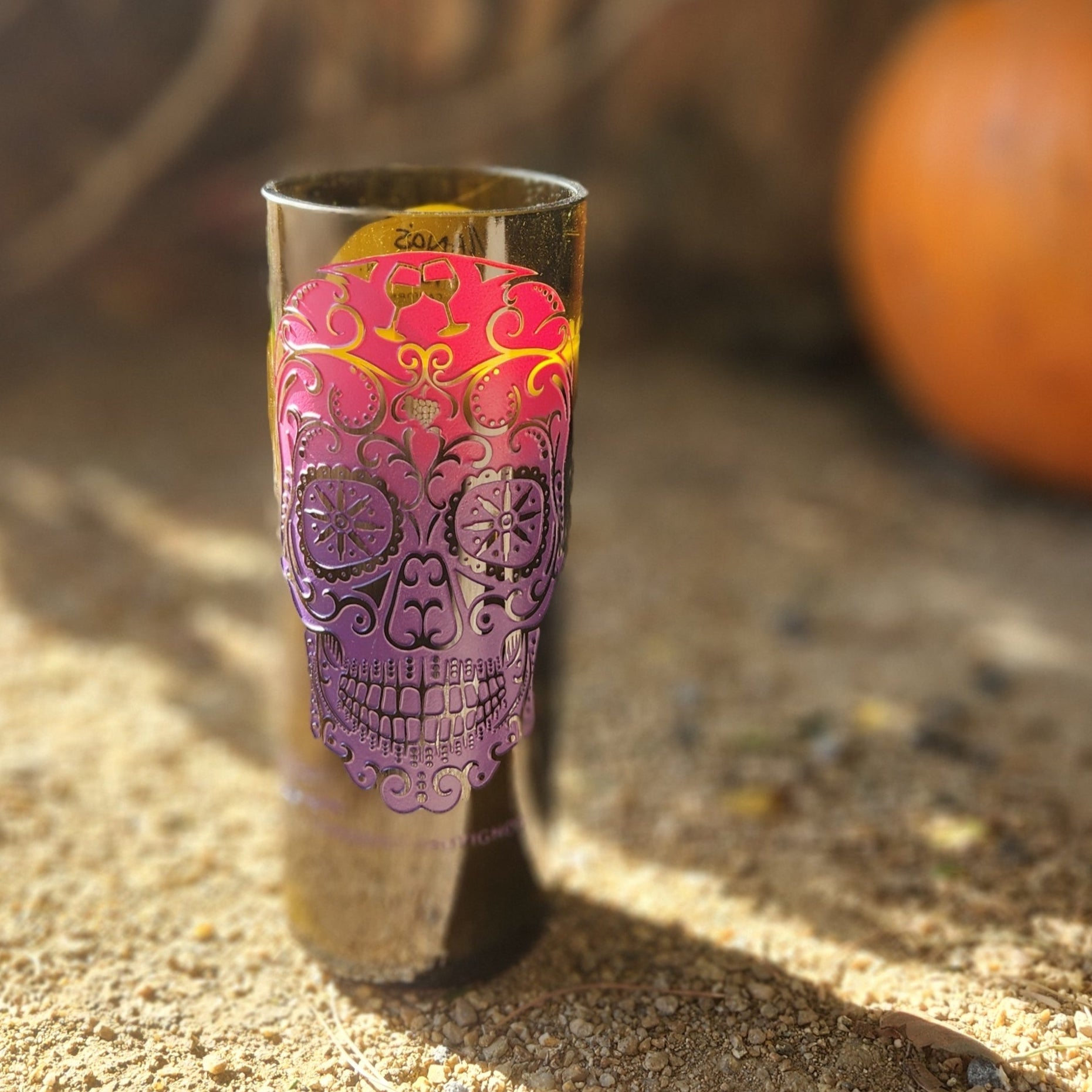 Add vibrant seasonal flair with this hand-poured candle in a recycled wine bottle. Featuring a colorful sugar skull design and set against a rustic autumn scene with a pumpkin, it’s perfect for celebrating fall and Día de los Muertos