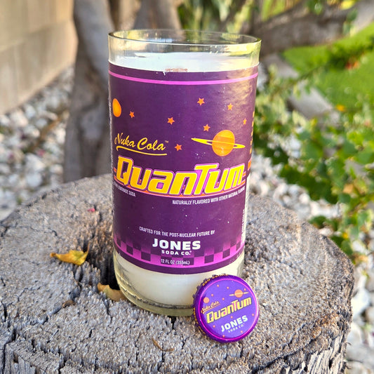 Candle in a glass jar with Nuka Cola Quantum label on a wooden stump.