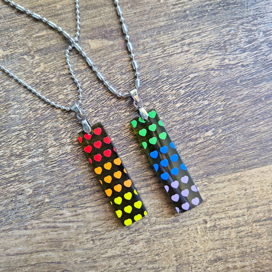 Two necklaces with colorful heart patterns on a wooden surface