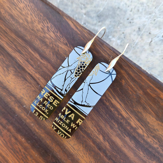 Earrings made from a cut wine bottle on a wooden tray.