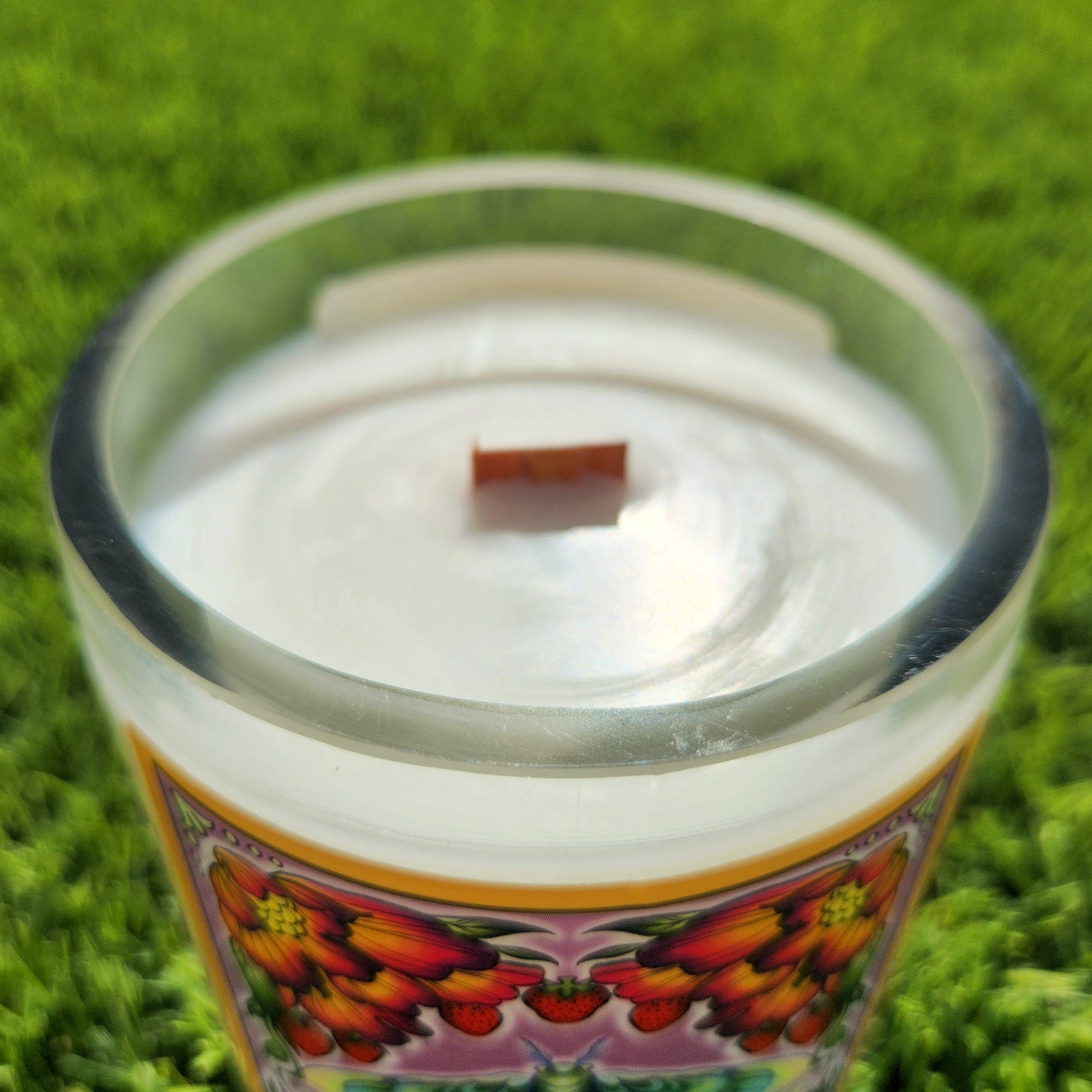 Close-up of the August candle’s rim, showcasing the clean white coconut soy wax and crackling wooden wick inside a clear, repurposed wine bottle. The thick, smooth glass rim reflects sunlight, giving a polished, handcrafted finish.