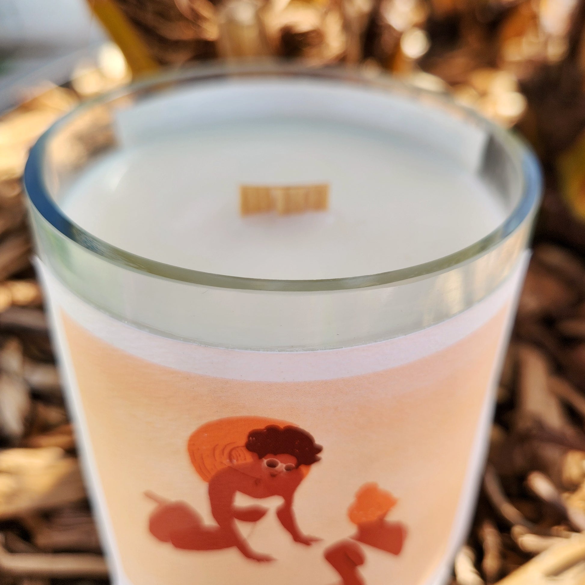 Close-up of a smooth rimmed recycled glass wine bottle candle, featuring a wooden wick and creamy coconut soy wax for a clean-burning, eco-conscious home accent.