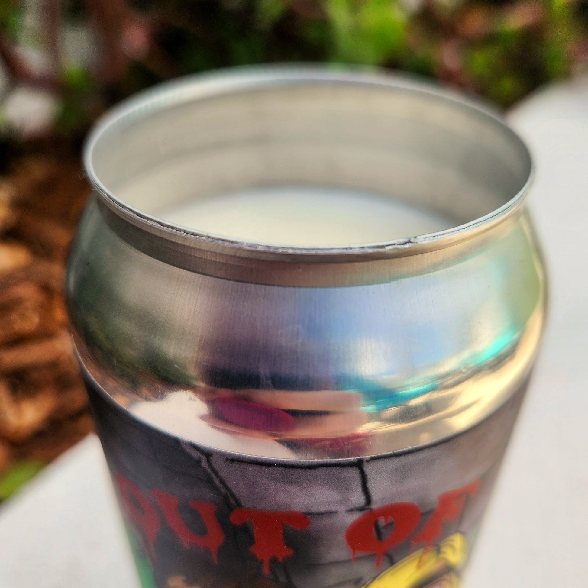 Close-up of the silver aluminum rim on the recycled RaR Brewing beer can candle. The shiny, smooth edge catches the light, highlighting the clean cut of the upcycled can and the creamy top layer of coconut soy wax just beneath it.