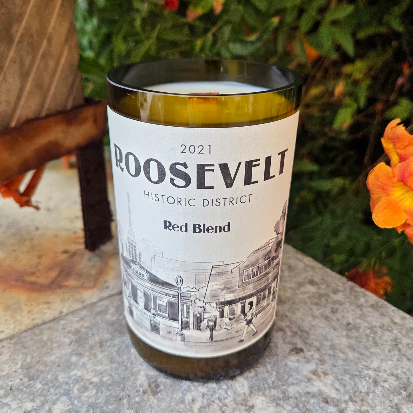 Wine Bottle Candle featuring artwork of the Phoenix Roosevelt Row neighborhood.  Sitting outside in front of bushes and flowers.