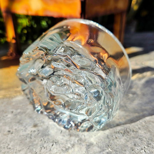 Clear glass with textured rose base on a stone surface
