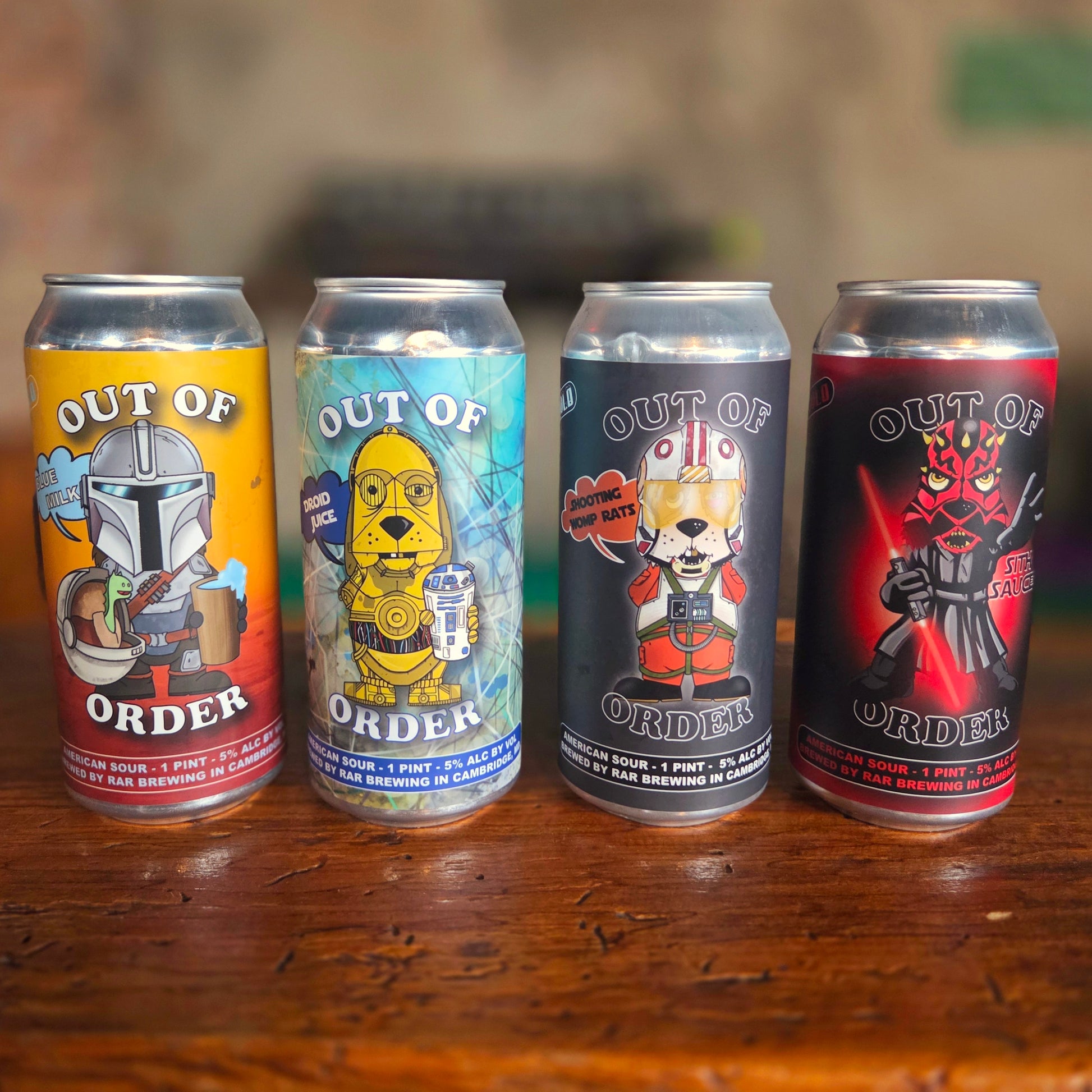 Front-facing shot of four handmade beer can candles, each in a RaR Brewing "Out of Order" can featuring playful Star Wars parody characters, now filled with clean-burning coconut soy wax and a centered wooden wick.