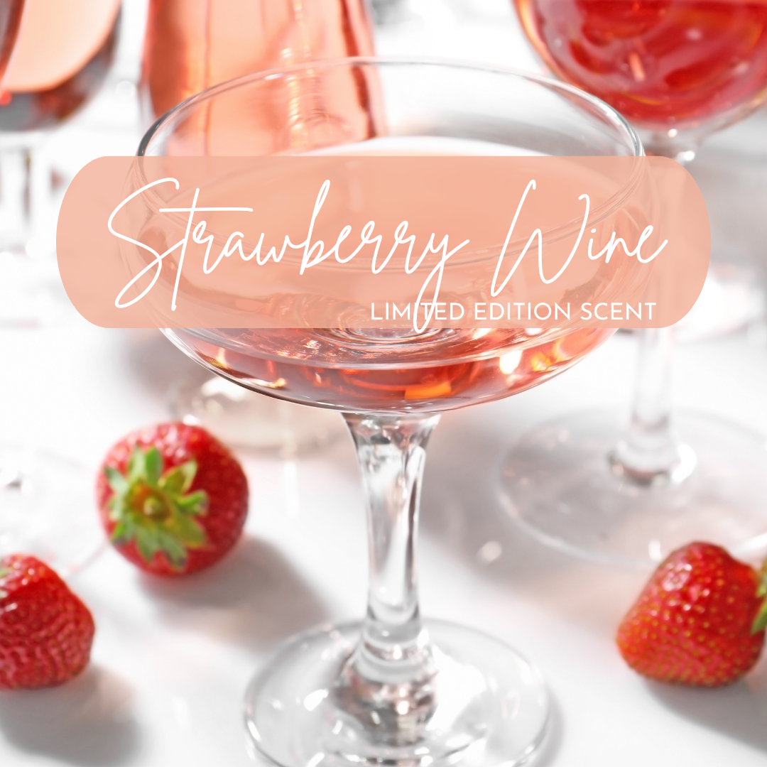 A close-up of elegant coupe and wine glasses filled with blush-pink strawberry wine, surrounded by fresh strawberries, used to promote the Strawberry Wine limited edition scent—bright, juicy, and sweetly nostalgic.