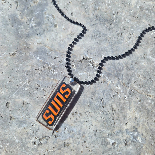 Necklace with a 'Suns' pendant on a textured surface