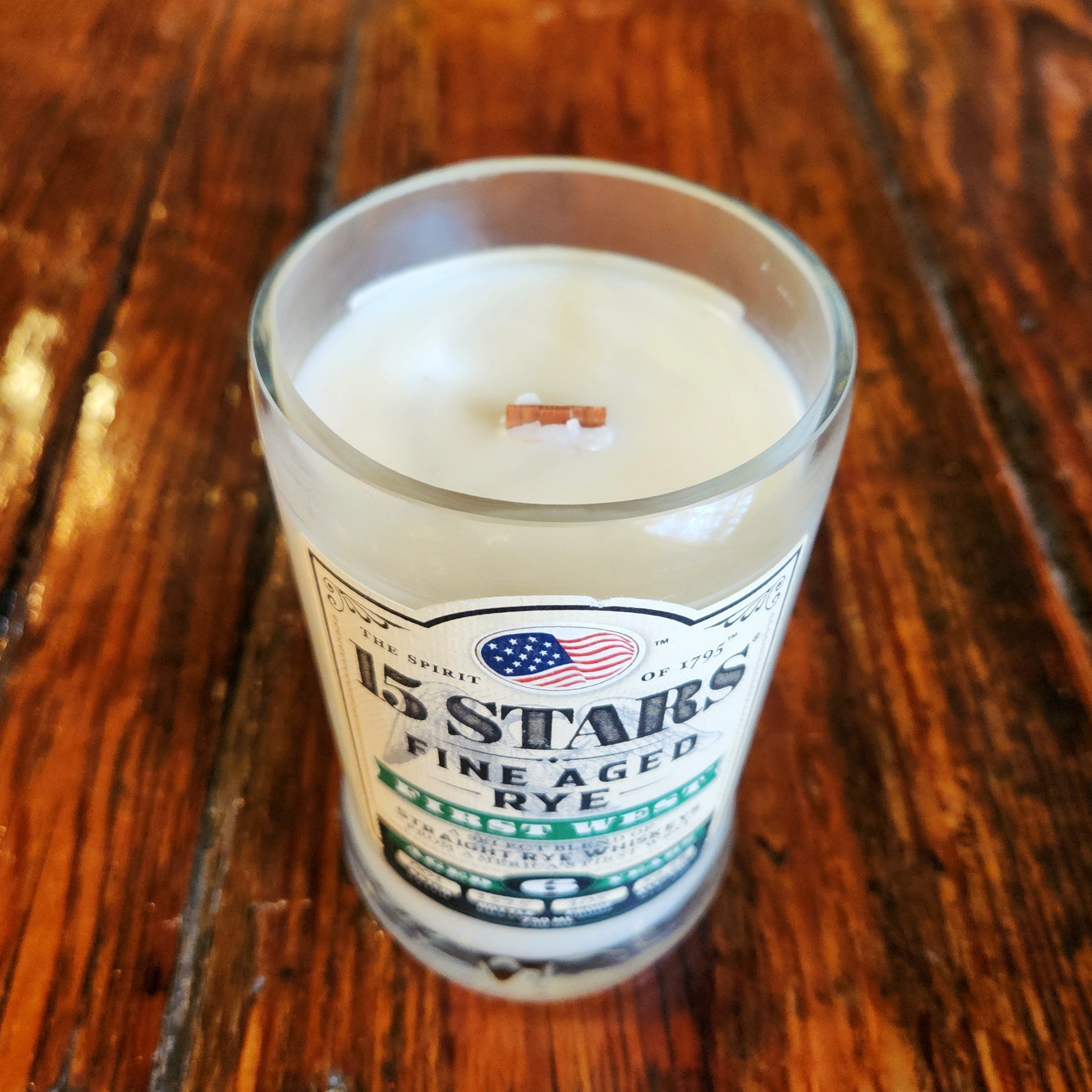 Angled top view of a handmade wooden wick candle in a 15 Stars liquor bottle with coconut soy wax for a clean, eco-conscious burn.