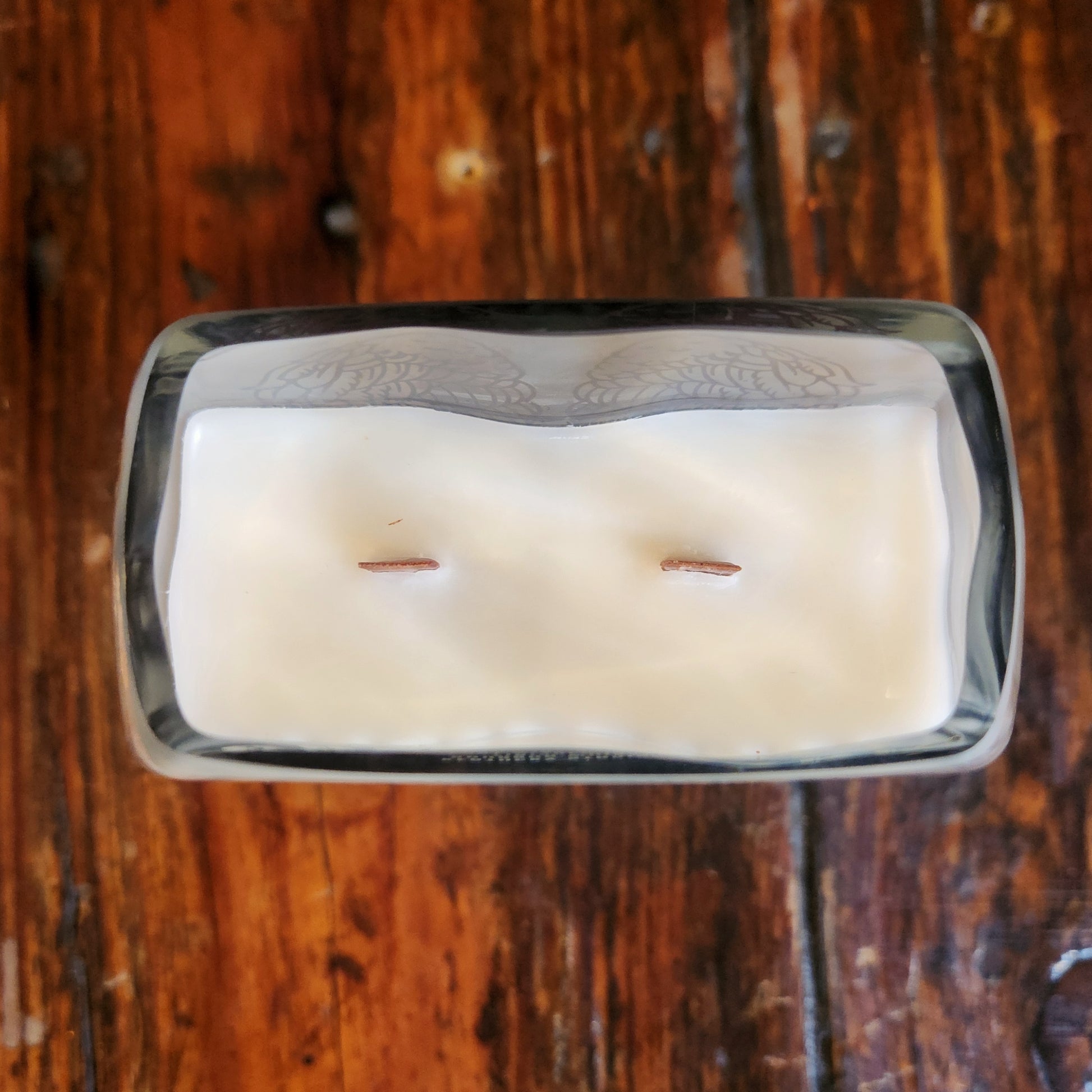 Top view of a clean-burning wooden wick candle made with coconut soy wax, hand-poured into a repurposed Angel’s Envy bourbon bottle with a rectangular shape.

