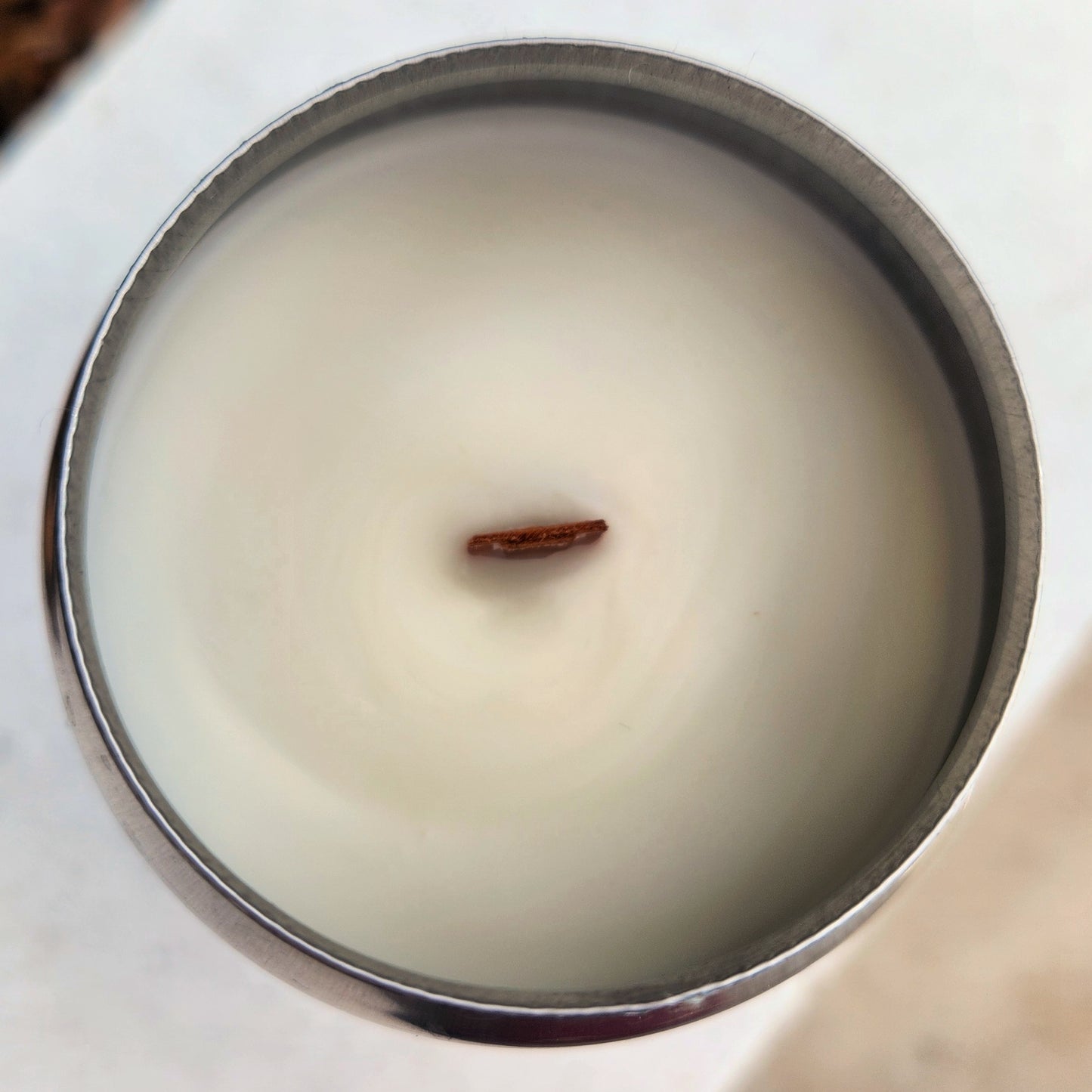 Overhead view of the eco-friendly RaR Brewing beer can candle. The creamy coconut soy wax surface is smooth and untouched, with a single centered wooden wick ready to burn. The can’s metallic rim surrounds the wax with a sleek silver finish.