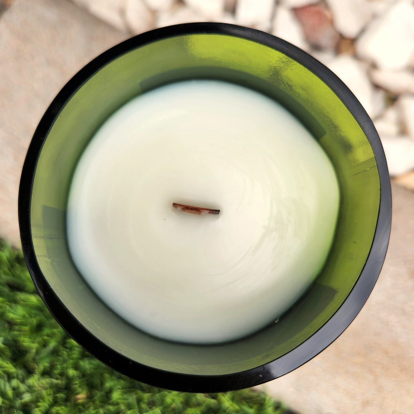 Top-down view of a clean-burning Frida Kahlo wine bottle candle with creamy white coconut soy wax and a centered wooden wick, hand-poured into a recycled green wine bottle with polished glass edges.