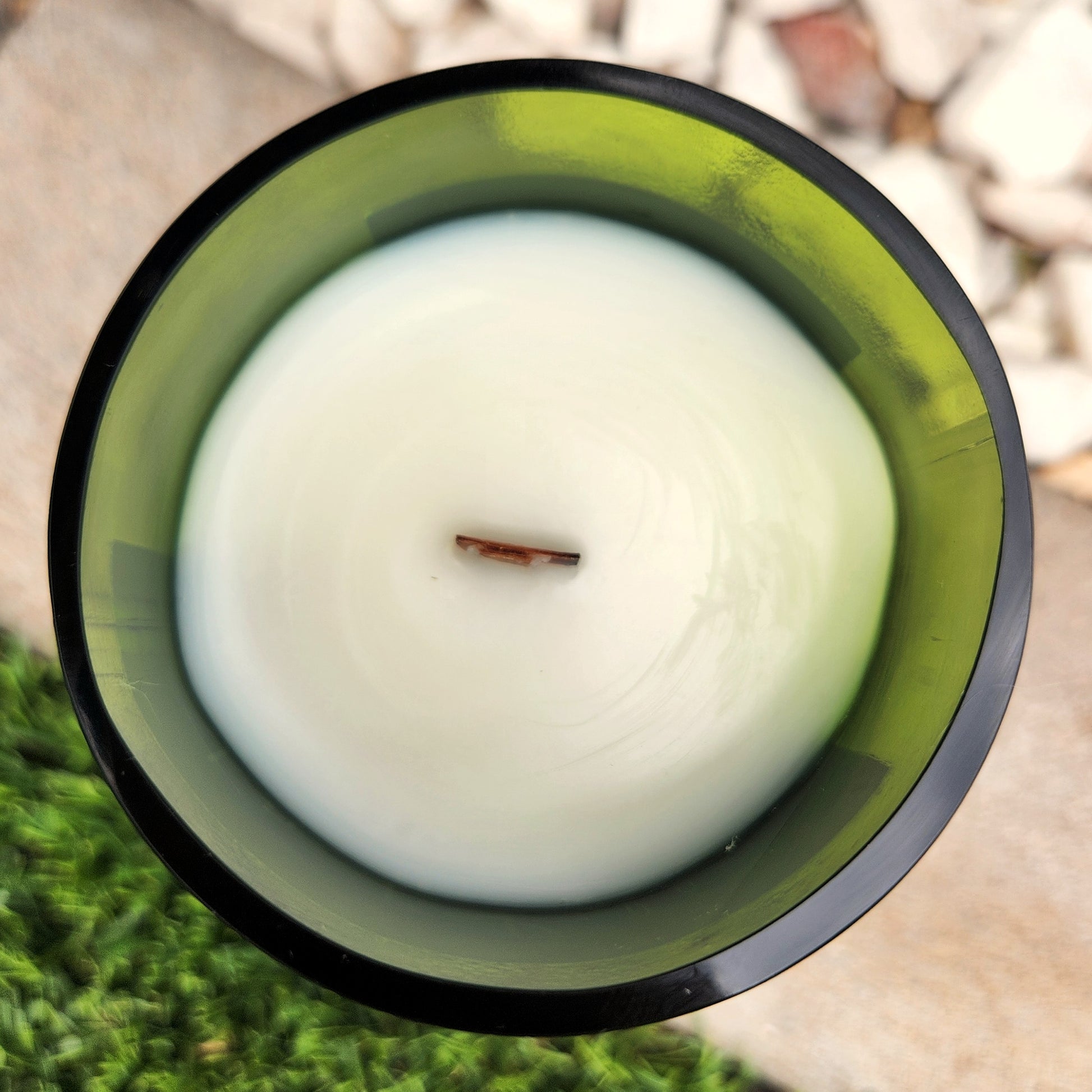 Top-down view of a clean-burning Frida Kahlo wine bottle candle with creamy white coconut soy wax and a centered wooden wick, hand-poured into a recycled green wine bottle with polished glass edges.