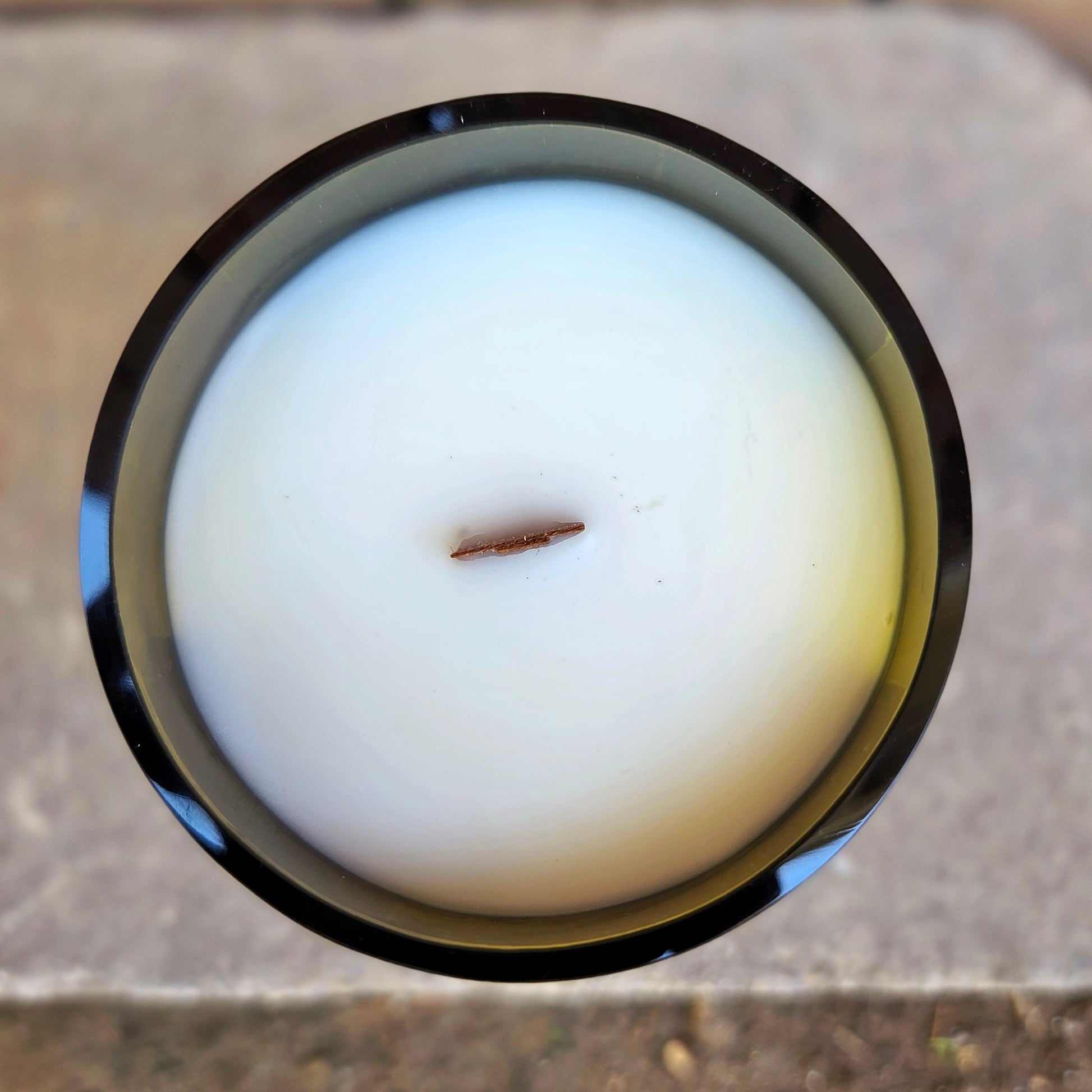 Top-down view of a handcrafted wine bottle candle with smooth white coconut soy wax and a centered wooden wick, showcasing the clean finish of this upcycled creation.