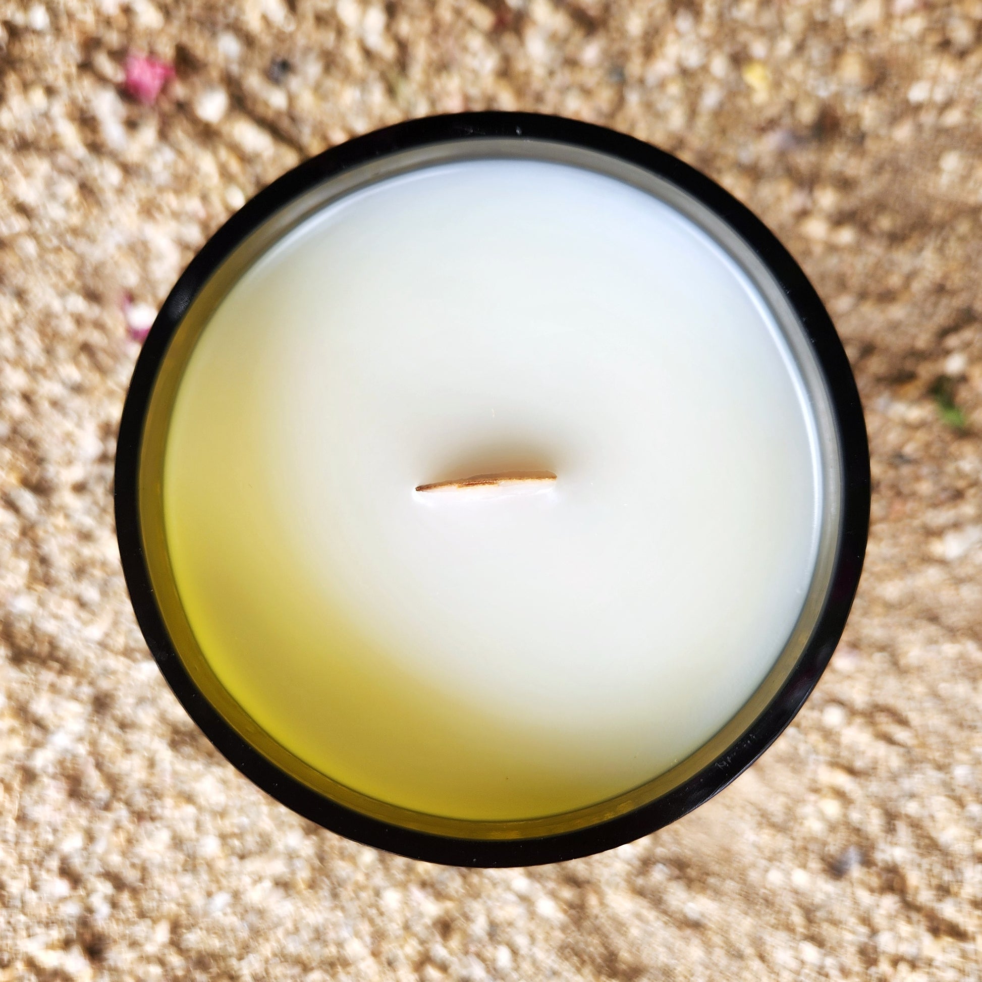 Top view of a clean-burning coconut soy wax candle with a wooden wick, hand-poured into a recycled wine bottle with a smooth glass rim. This eco-friendly candle is part of the fantasy-inspired House of the Dragon collection.
