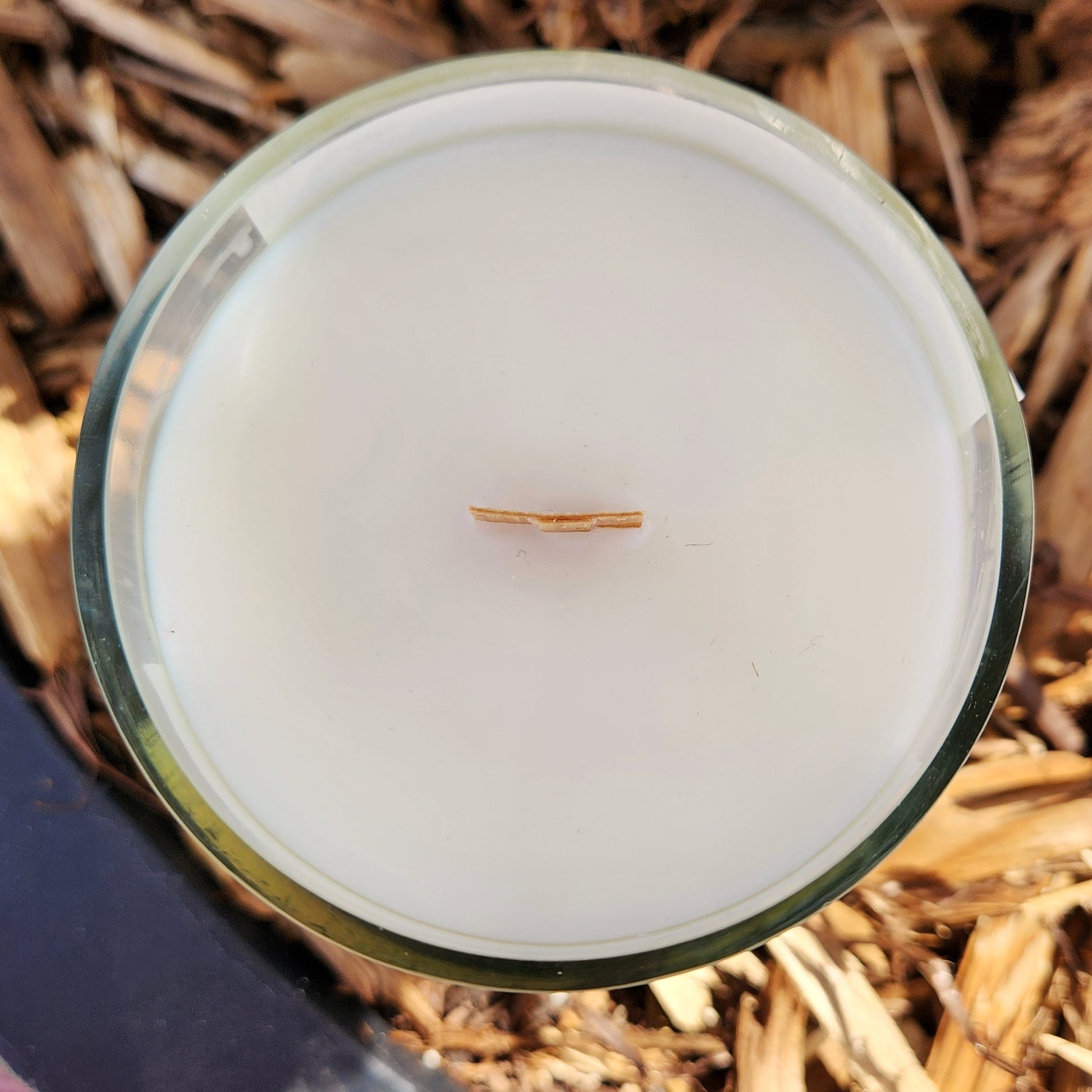 Top-down view of a clean-burning coconut soy wax candle with a wooden wick, housed in a recycled wine bottle. Eco-friendly and sustainable home fragrance option.