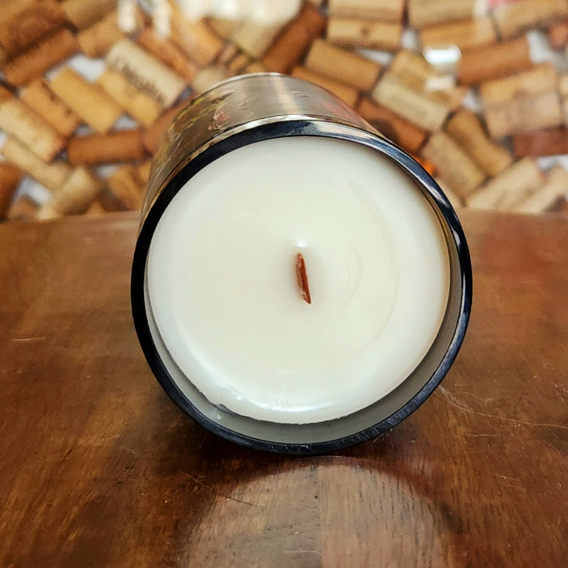 Bird’s-eye view of a hand-poured coconut soy candle in a recycled brown bottle with a centered wooden wick. The wax surface is smooth and creamy, emphasizing its clean, non-toxic burn.