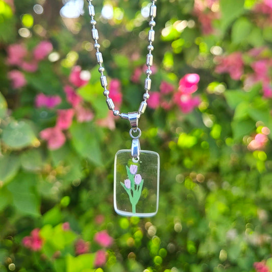 Necklace with a glass pendant featuring a tulip design against a blurred natural background