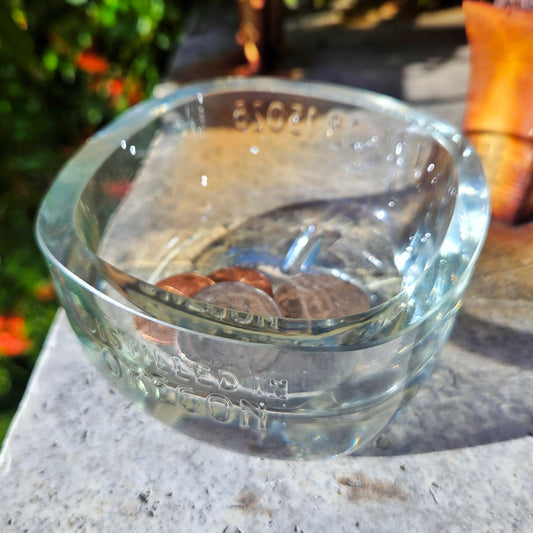 Clear glass bowl with coins inside on a stone surface