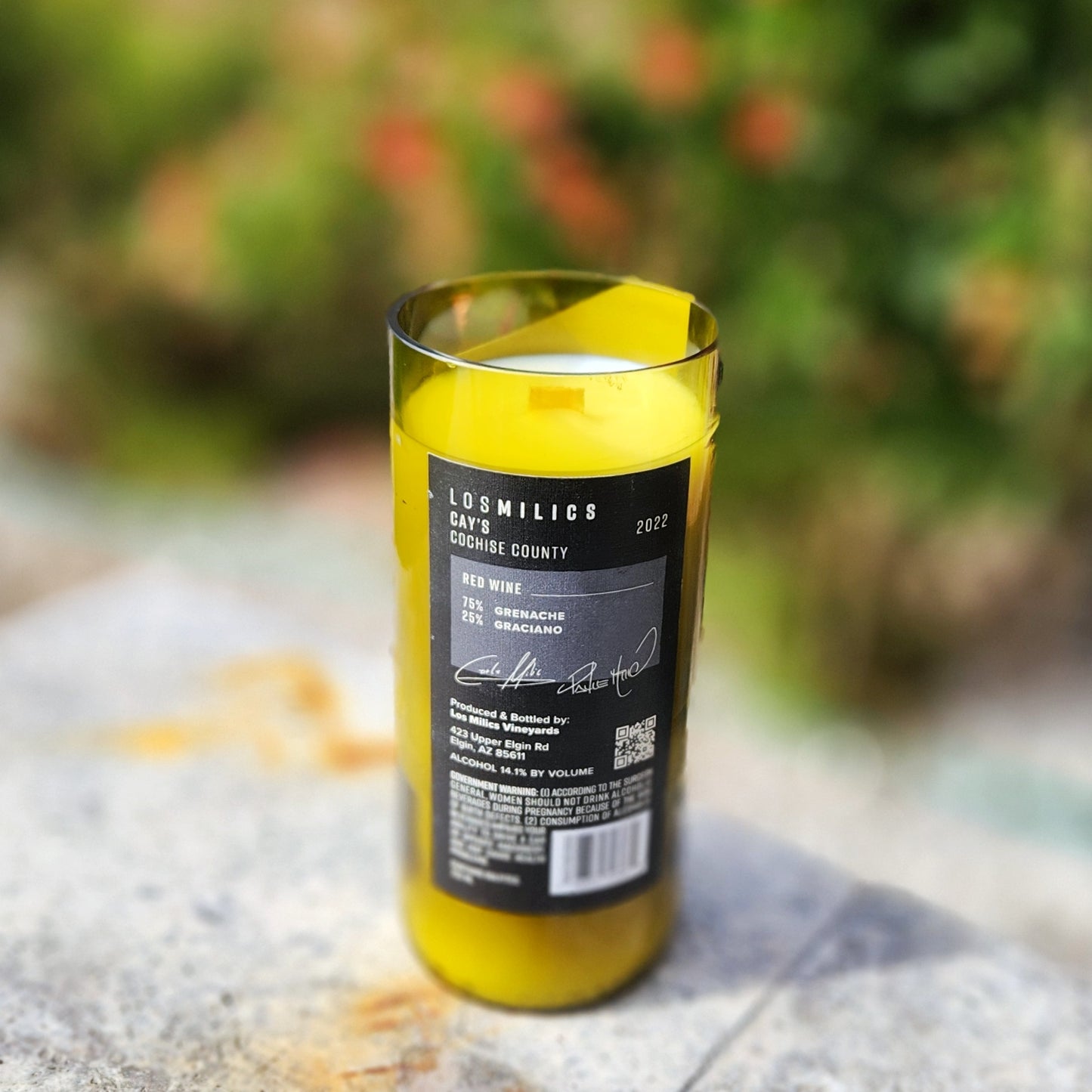 Back of a Los Milics wine bottle candle showing wine origin details and eco-conscious upcycling, with smooth polished rim and hand-poured coconut soy wax inside.