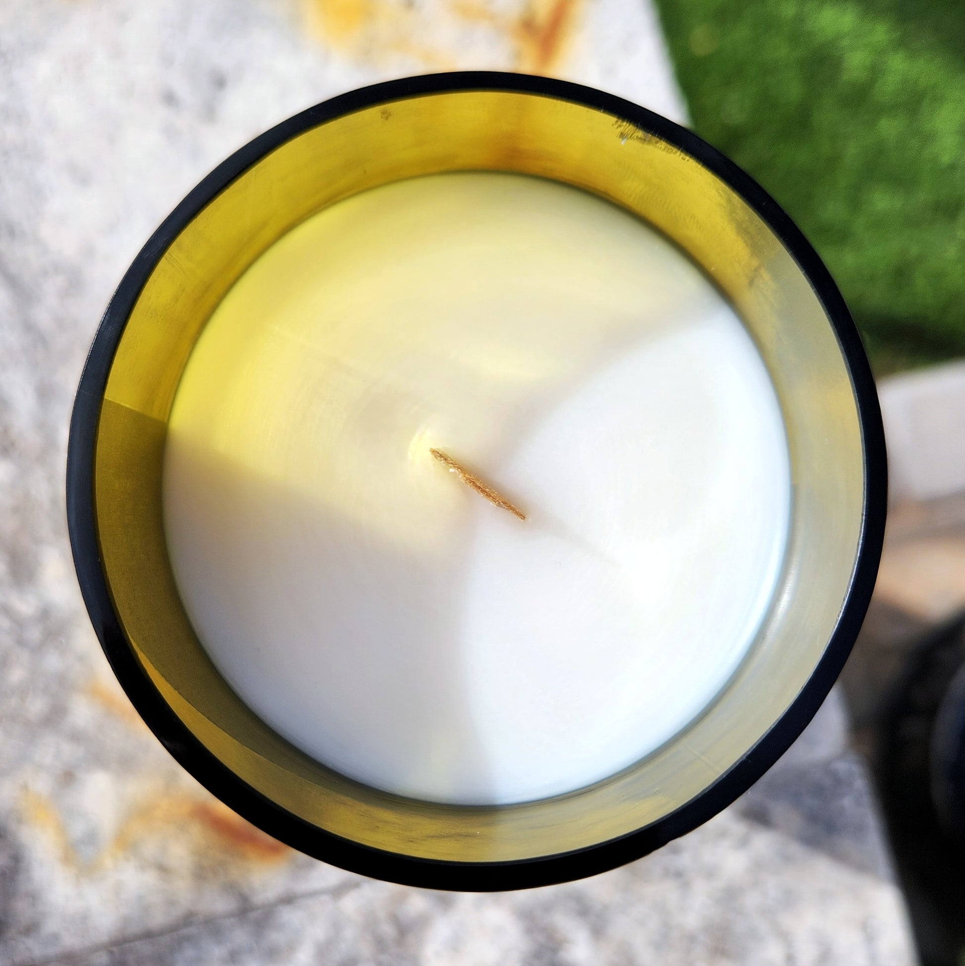Top-down image of a clean-burning wine bottle candle with creamy white coconut soy wax and a centered wooden wick inside a yellow recycled Los Milics bottle.

