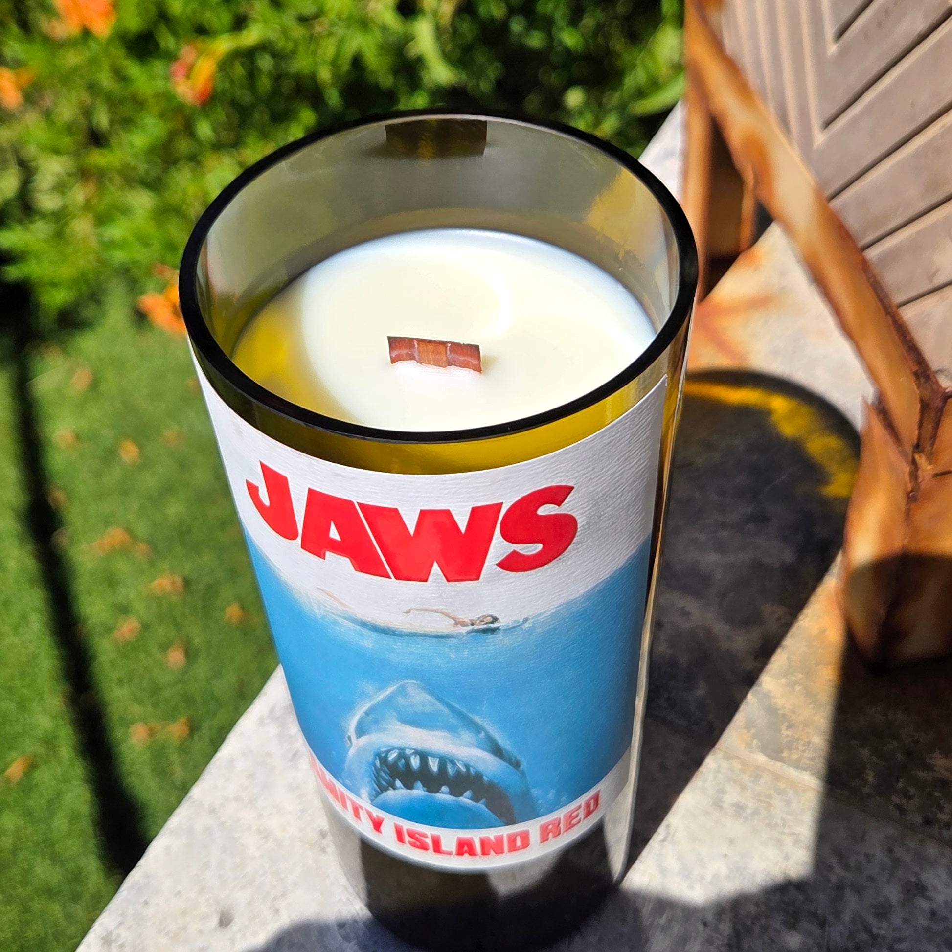 Top-down angled view of a Jaws inspired wine bottle candle featuring the iconic shark label, hand-poured with coconut soy wax and a crackling wooden wick.