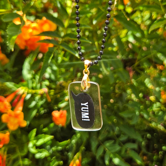 Glass milk bottle Necklace with a pendant labeled 'YUMI' against a green foliage background