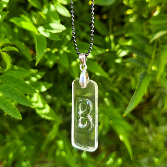 Letter B initial necklace made from clear recycled whiskey bottle glass with original raised lettering
