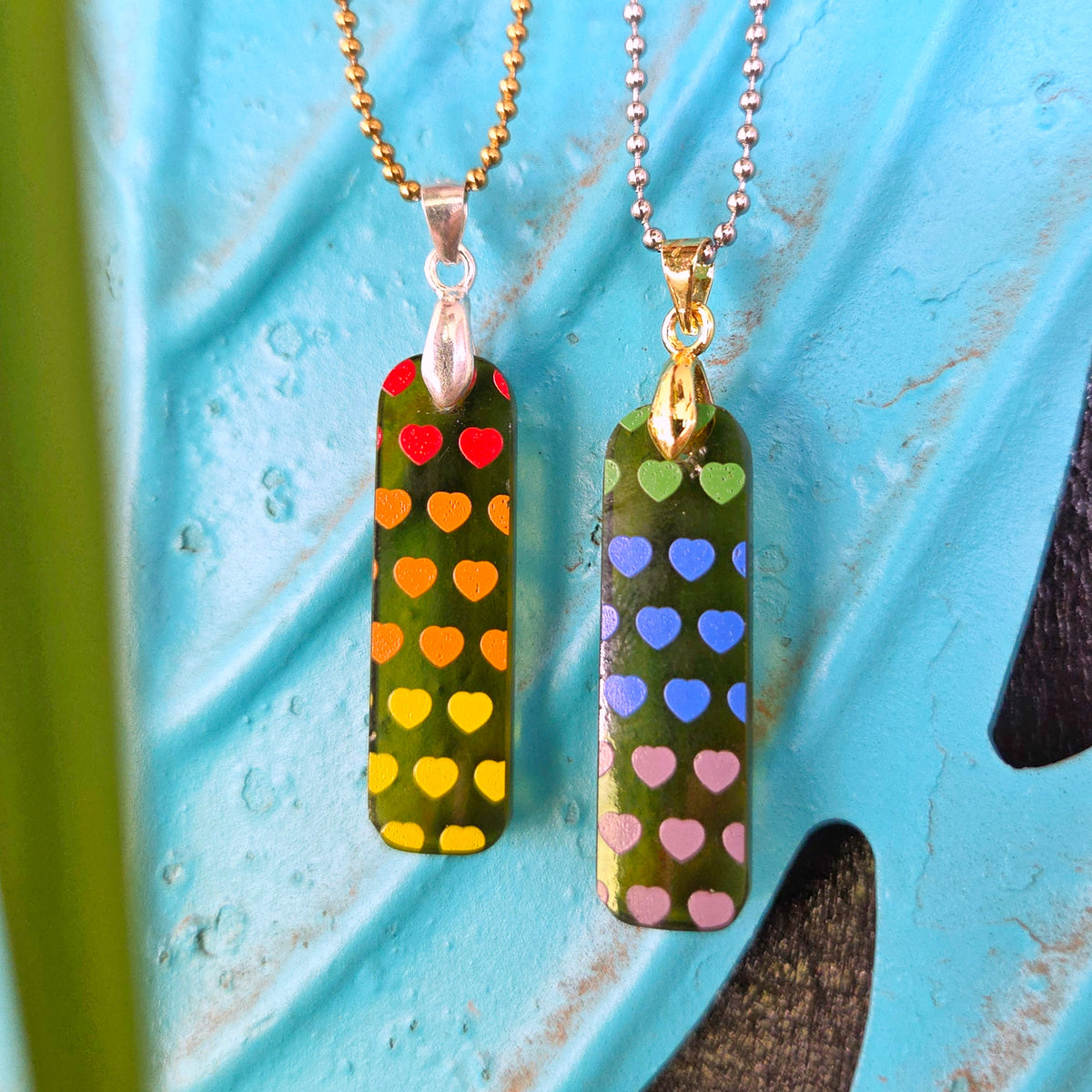 Close-up of two matching friendship necklaces made from recycled Prosecco bottle glass with multicolor heart designs