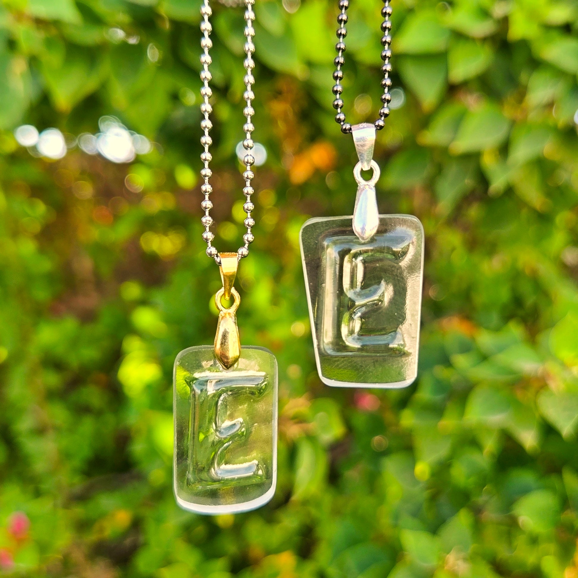 Two Letter E initial necklaces made from clear recycled whiskey bottle glass with original raised lettering