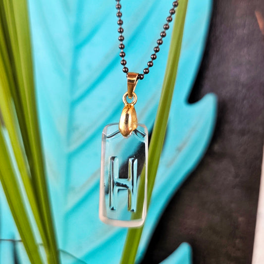 Letter H initial necklace made from clear recycled liquor bottle glass with original raised lettering